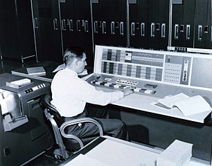 man using a mainframe console, with mainframe in background