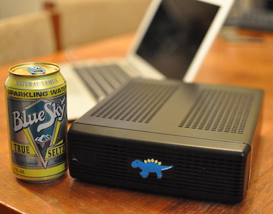 very small computer next to soda can and laptop